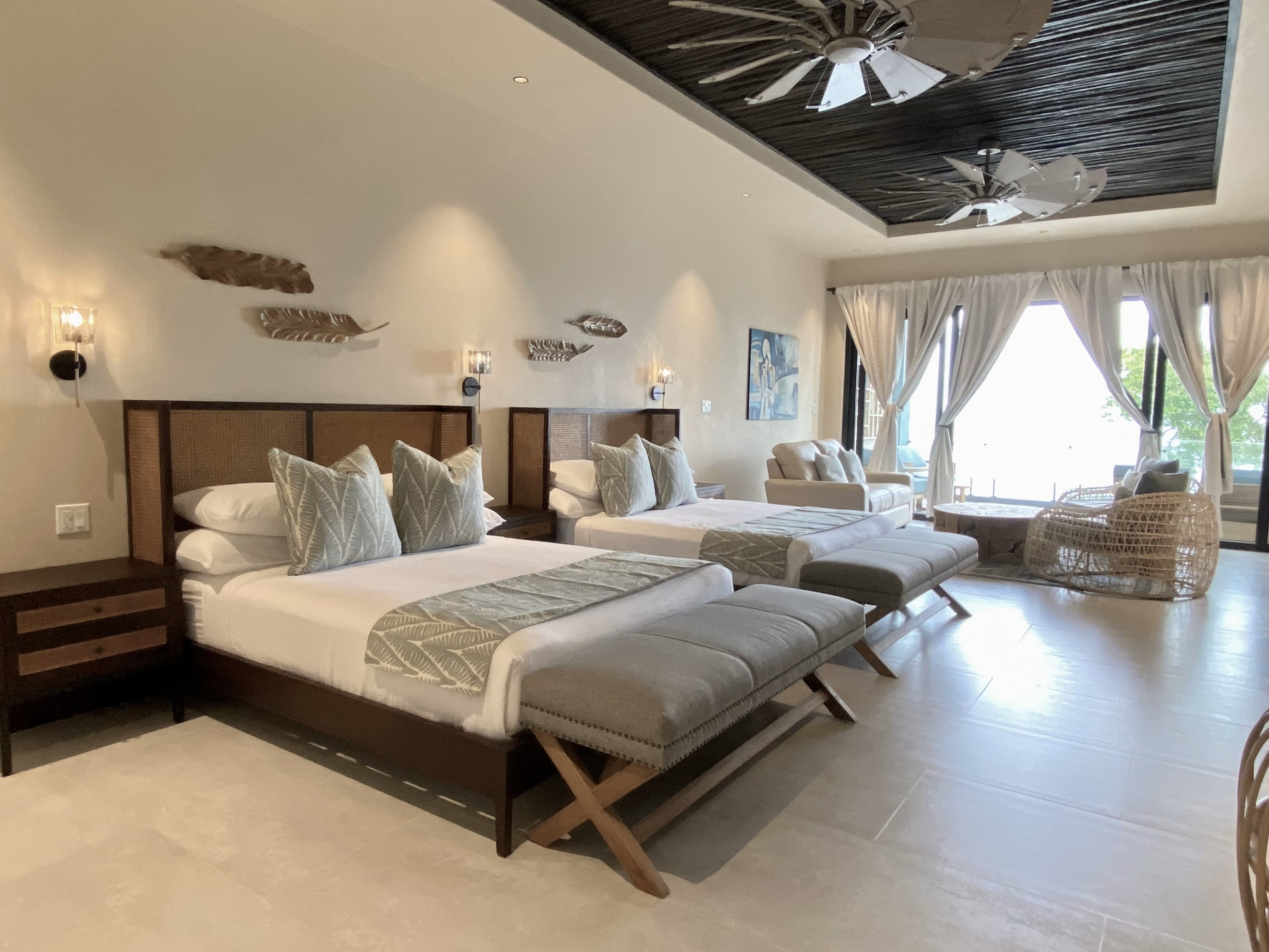 A modern hotel room featuring two beds, stylish furnishings, and large windows with a view.