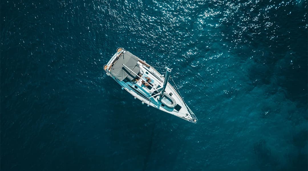 Aerial view of a sailboat on deep blue water.
