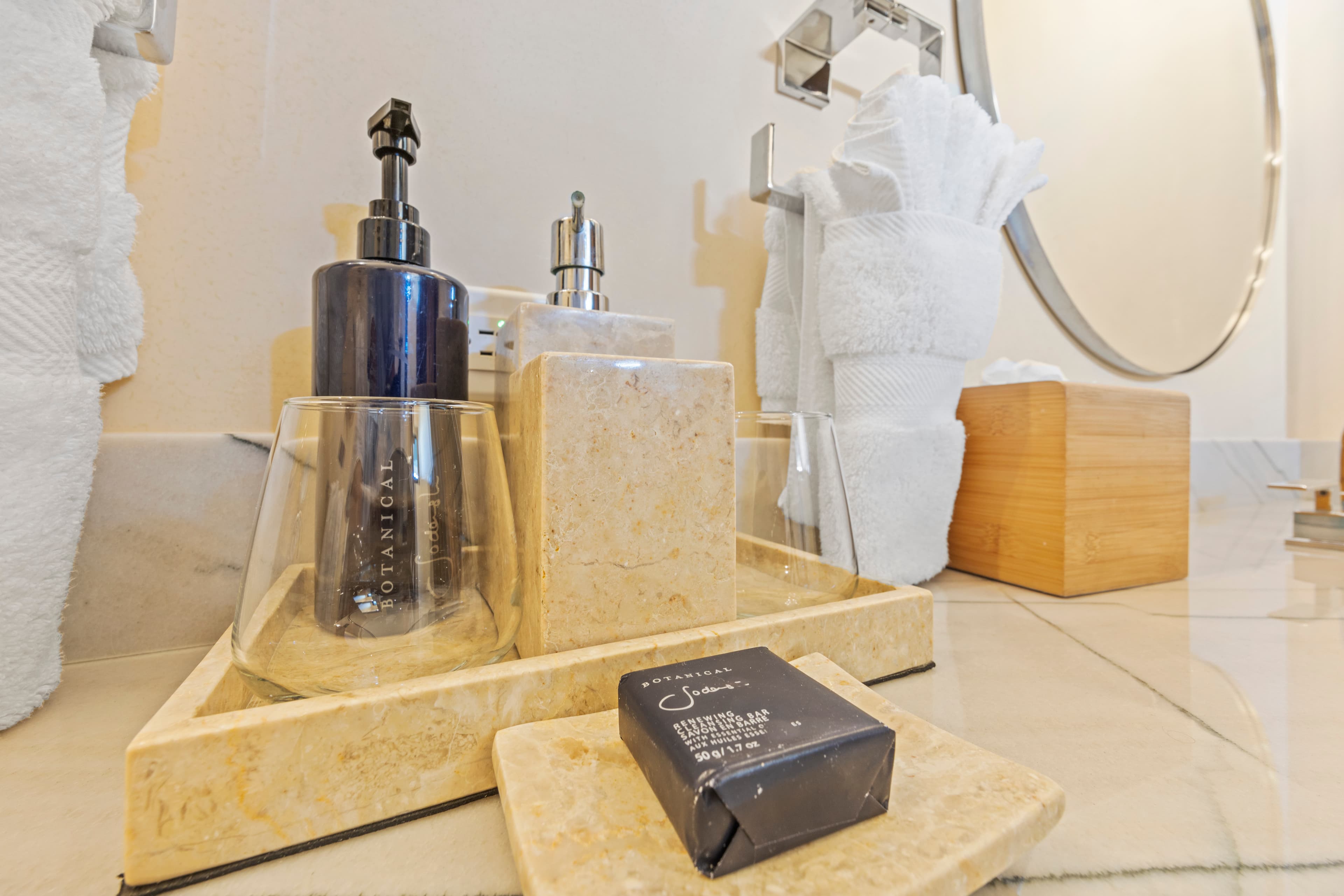 A bathroom countertop featuring a soap dispenser, lotion bottle, a bar of soap, and neatly folded towels.
