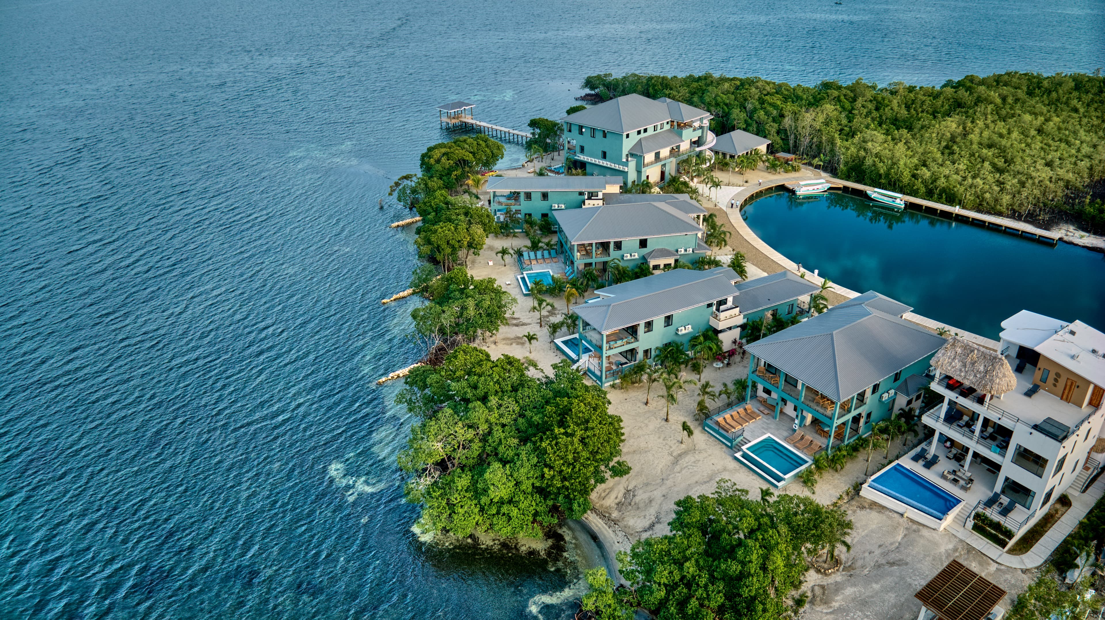 Aerial view of a coastal resort with modern buildings surrounded by water and greenery.