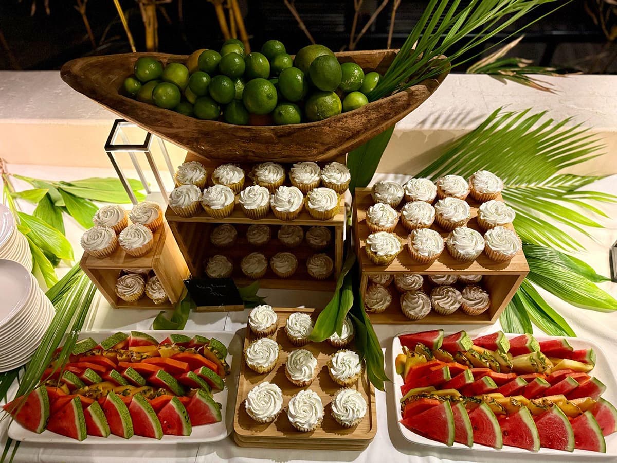 A vibrant display of cupcakes, fruit slices, and limes arranged elegantly on a buffet table.