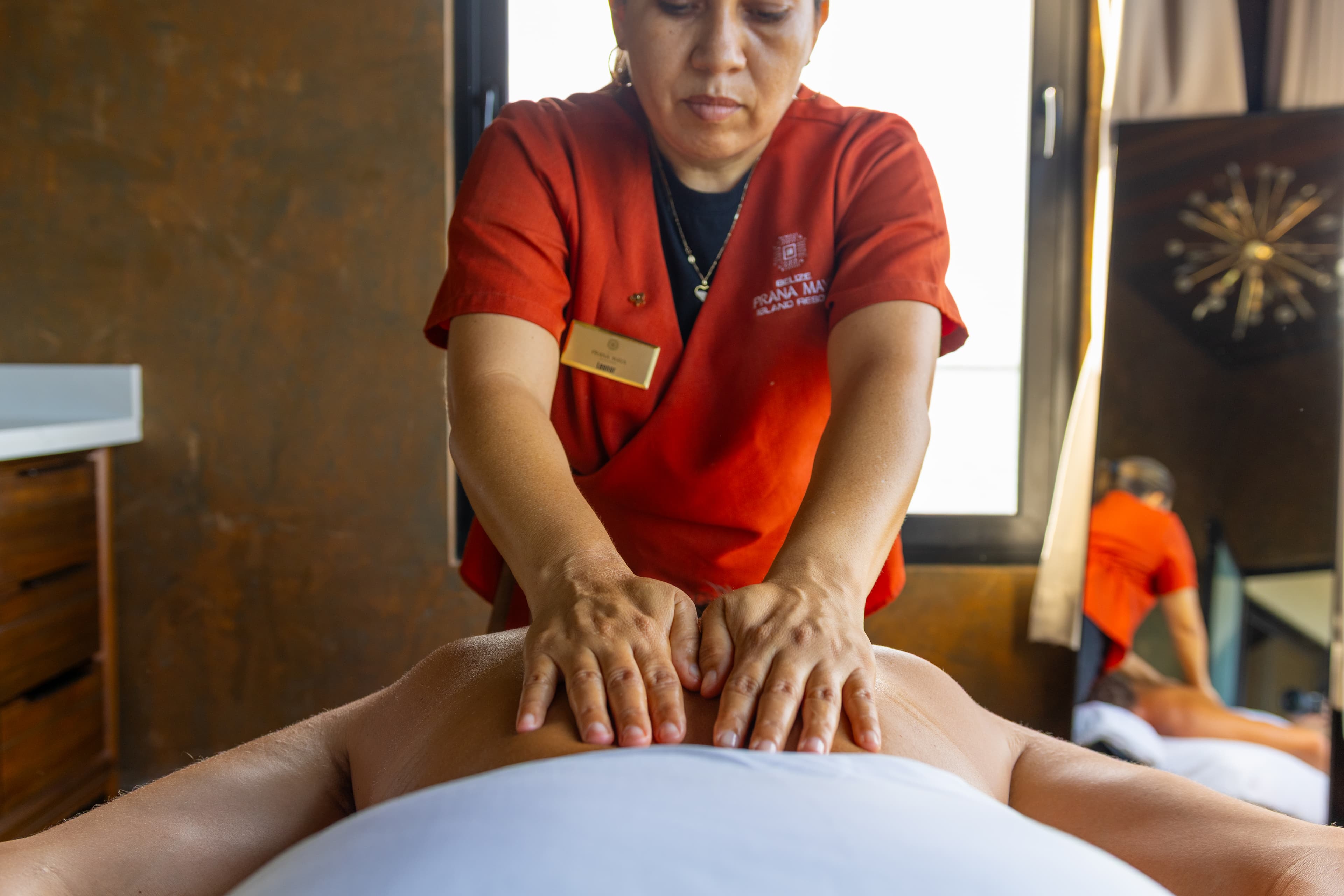 A masseuse applies pressure to a client's back during a massage session.