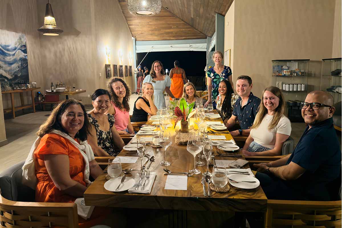 A group of ten people seated around a beautifully set dinner table in a well-lit restaurant.