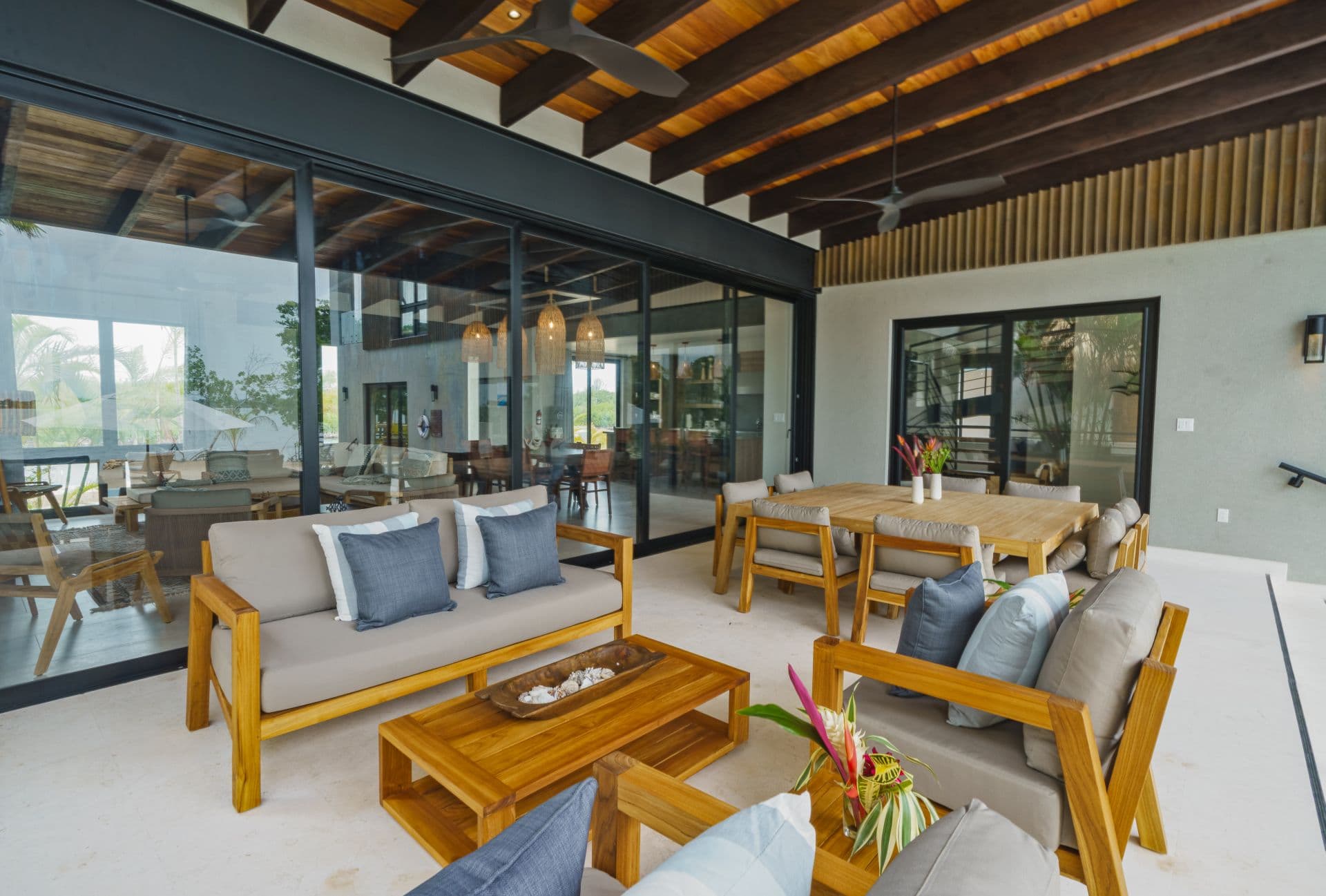 A stylish outdoor seating area featuring wooden furniture and modern decor with large glass windows.