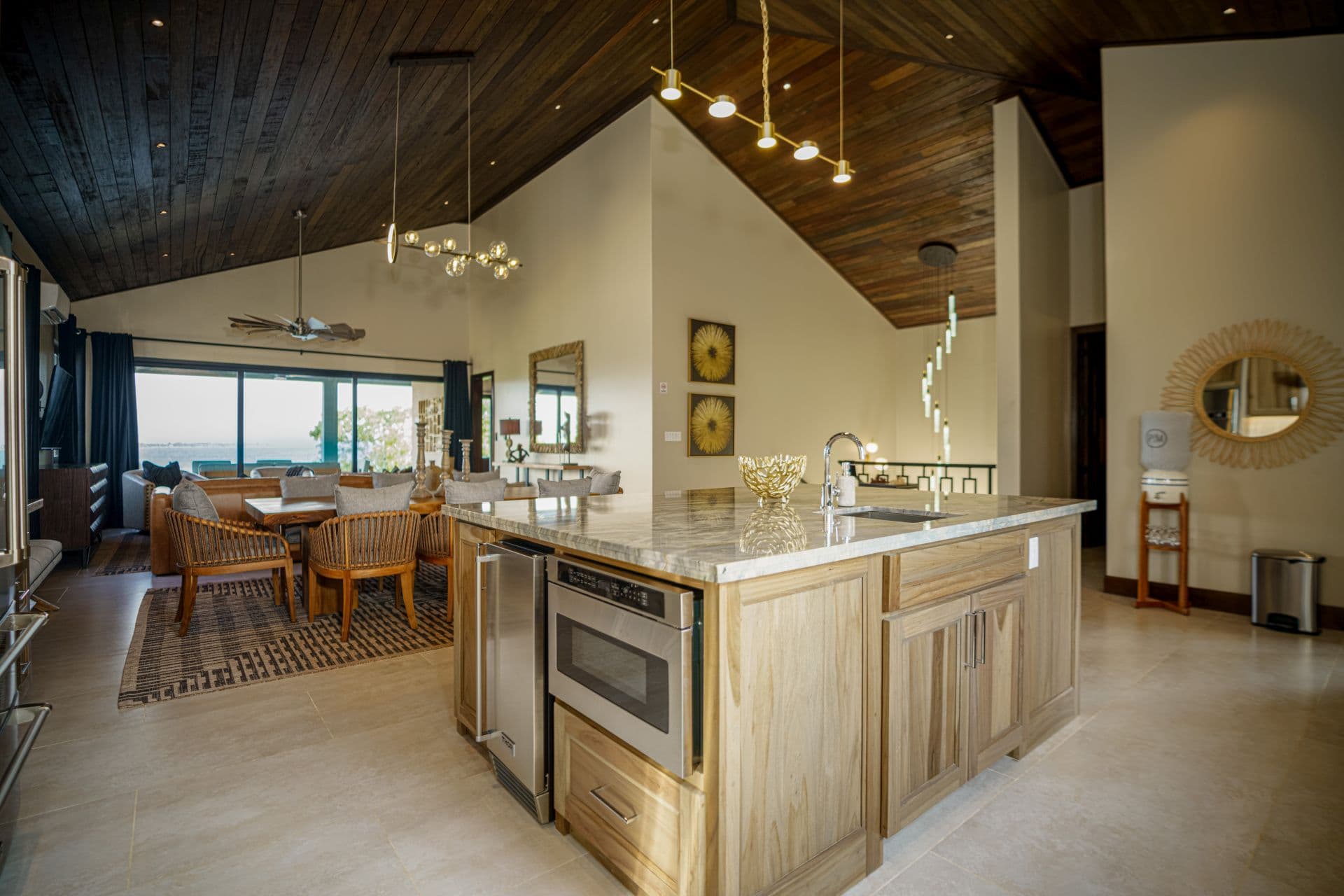 Modern kitchen with wooden accents, an island, and large windows overlooking a scenic view.