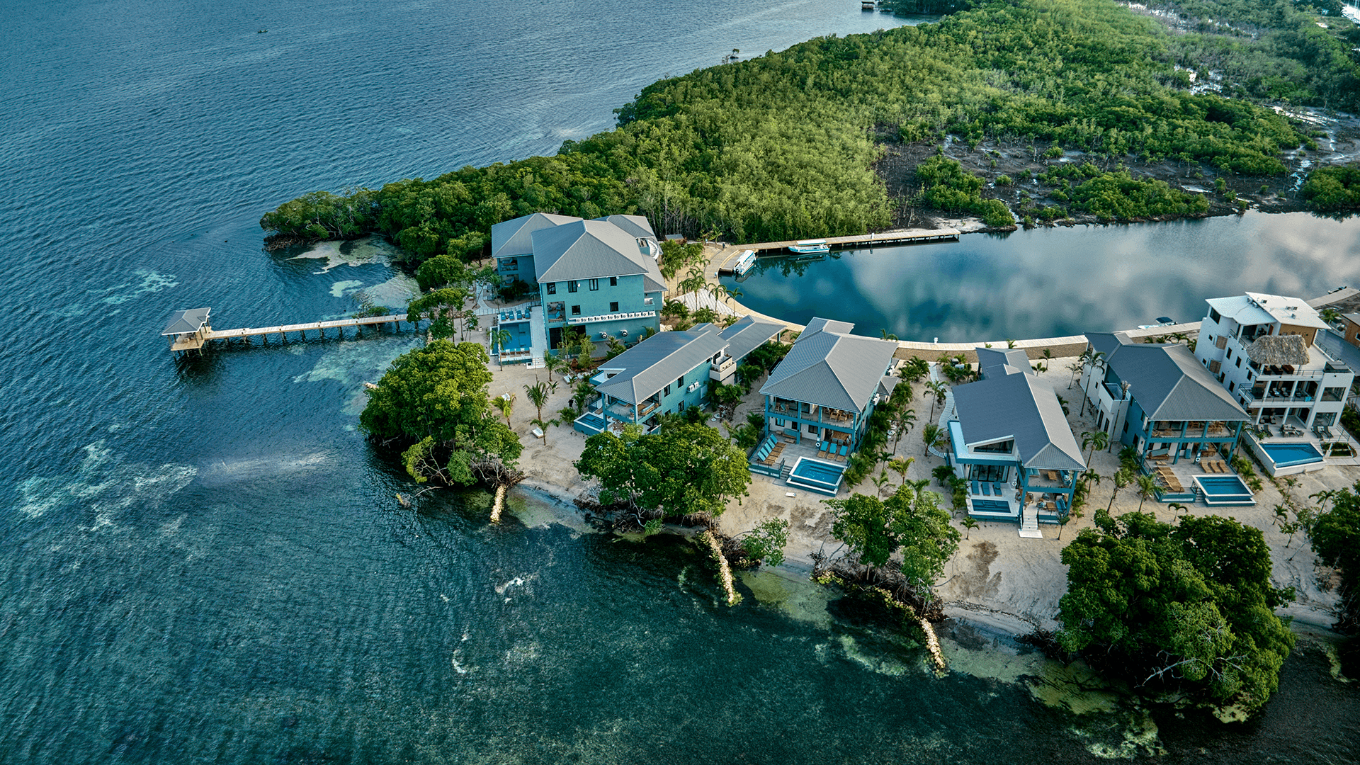 Aerial view of a coastal resort with multiple buildings surrounded by water and vegetation.
