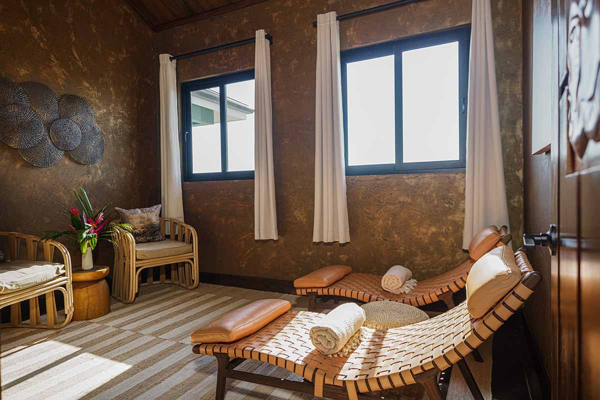 A serene room featuring bamboo furniture, large windows, and soft lighting, accented with towels and decorative elements.
