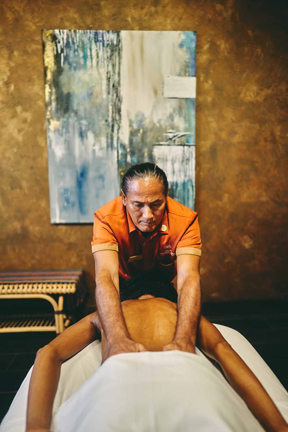 A massage therapist gives a back massage to a client in a spa setting.