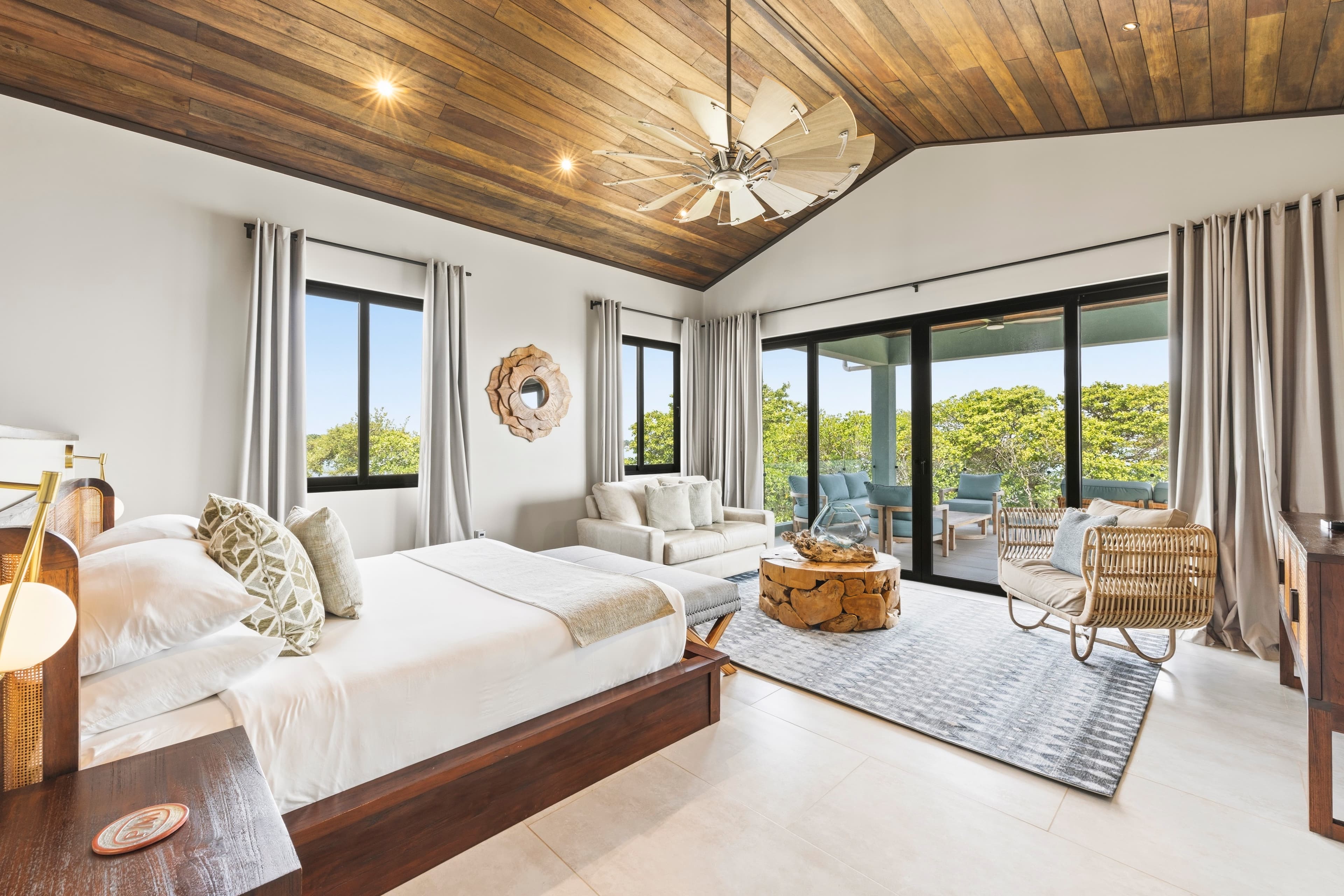 A modern bedroom featuring a wooden ceiling, large windows, and minimalist décor.