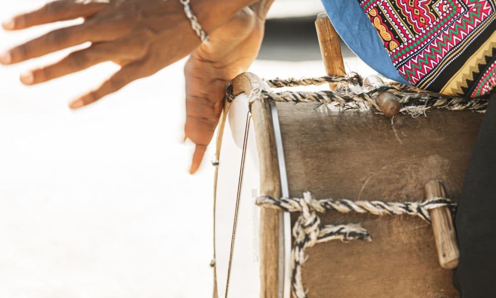 Close-up of hands drumming on a traditional Garifuna drum.