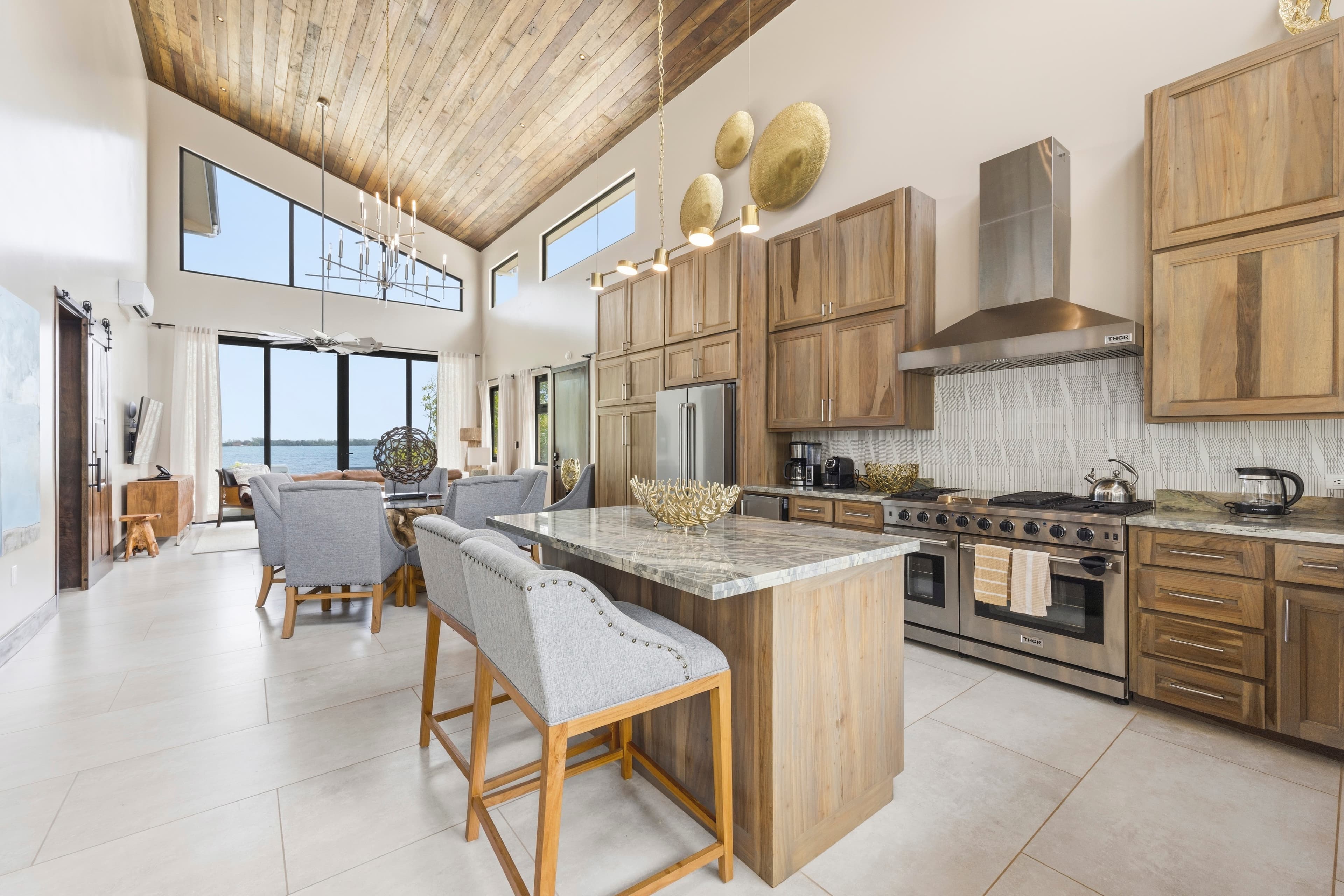 A modern kitchen with wooden cabinetry, a spacious island, and large windows offering a scenic view.