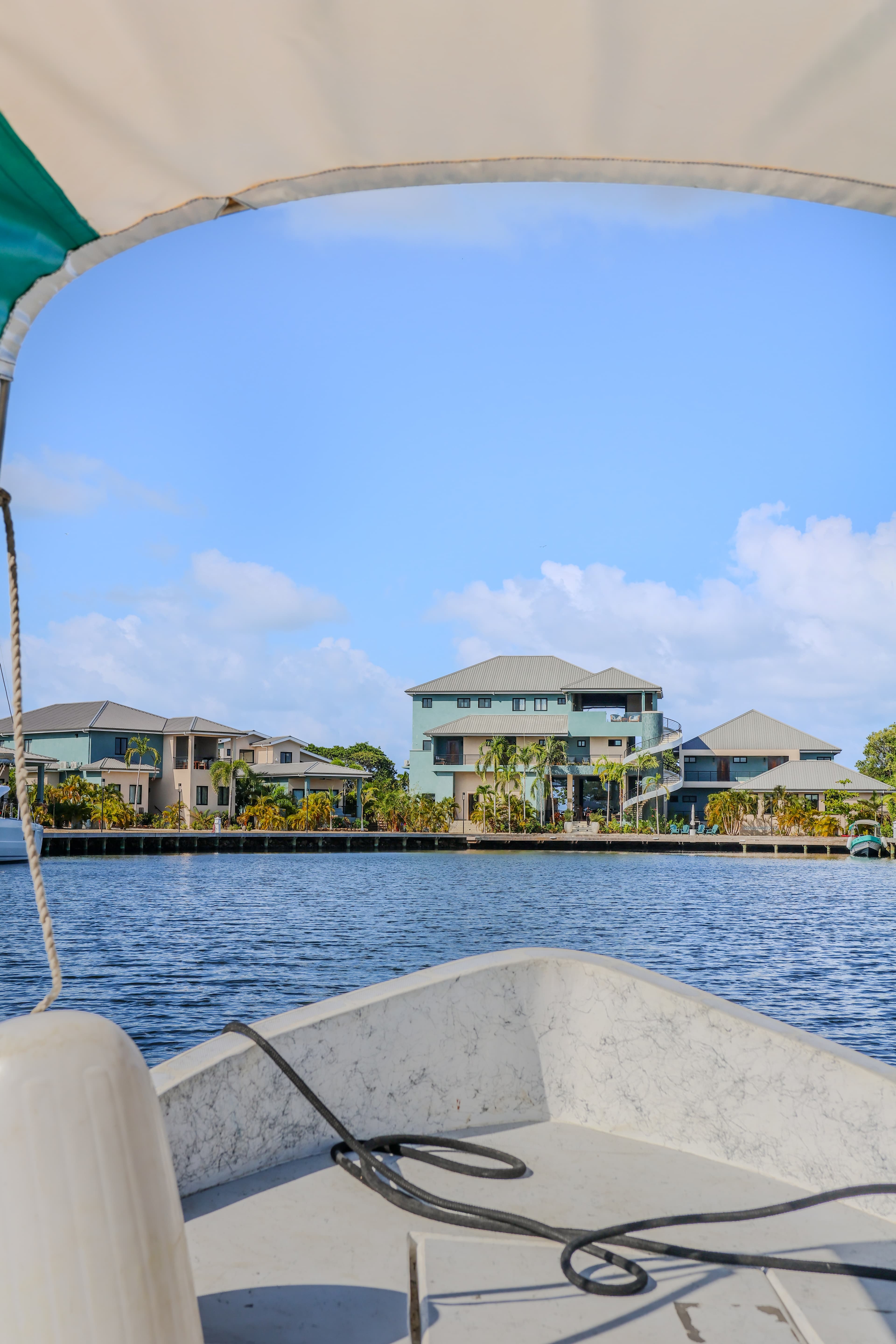 View from the front of a boat looking towards houses along a waterway under a blue sky.