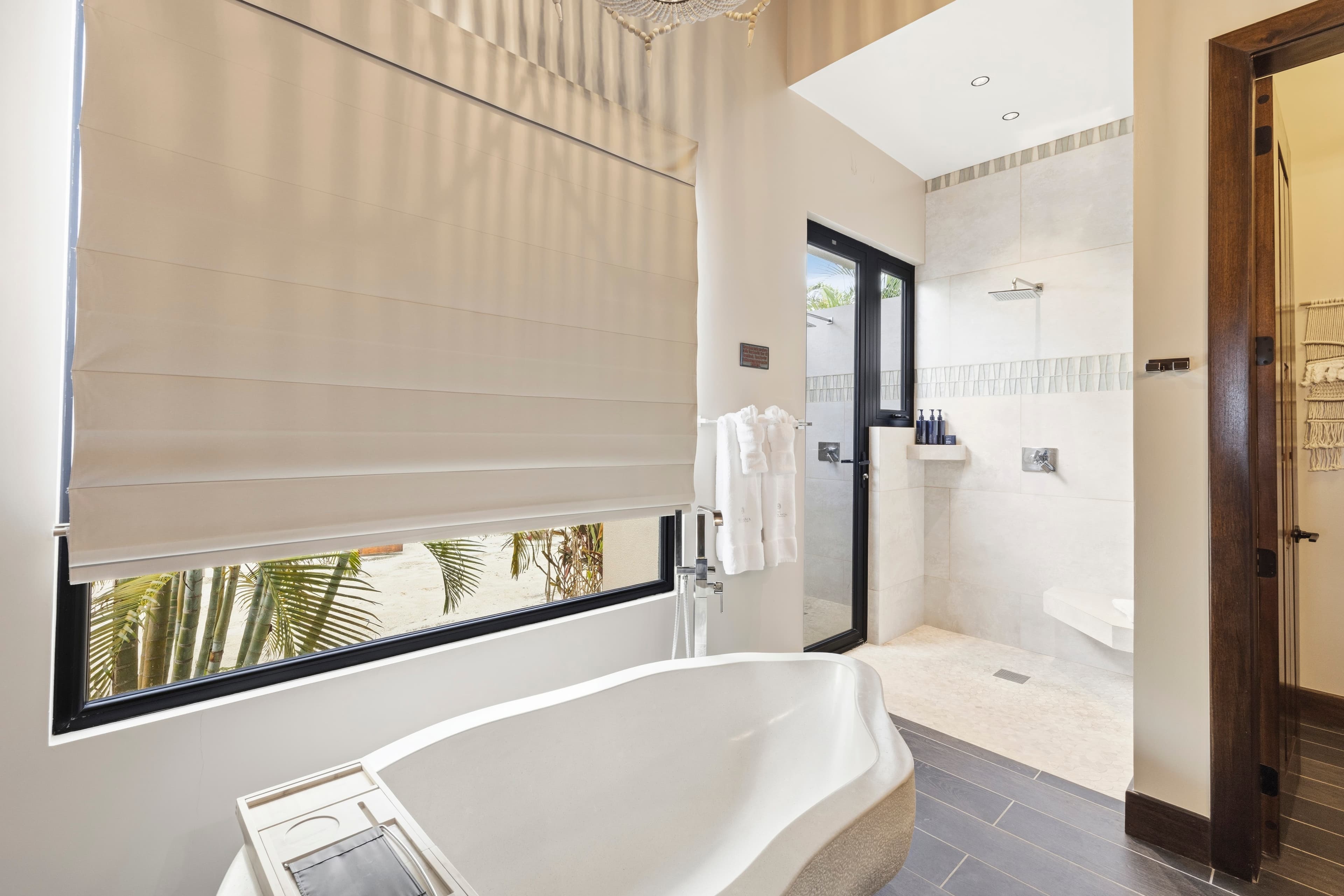 A modern bathroom featuring a freestanding tub, a walk-in shower, and large windows with natural light.