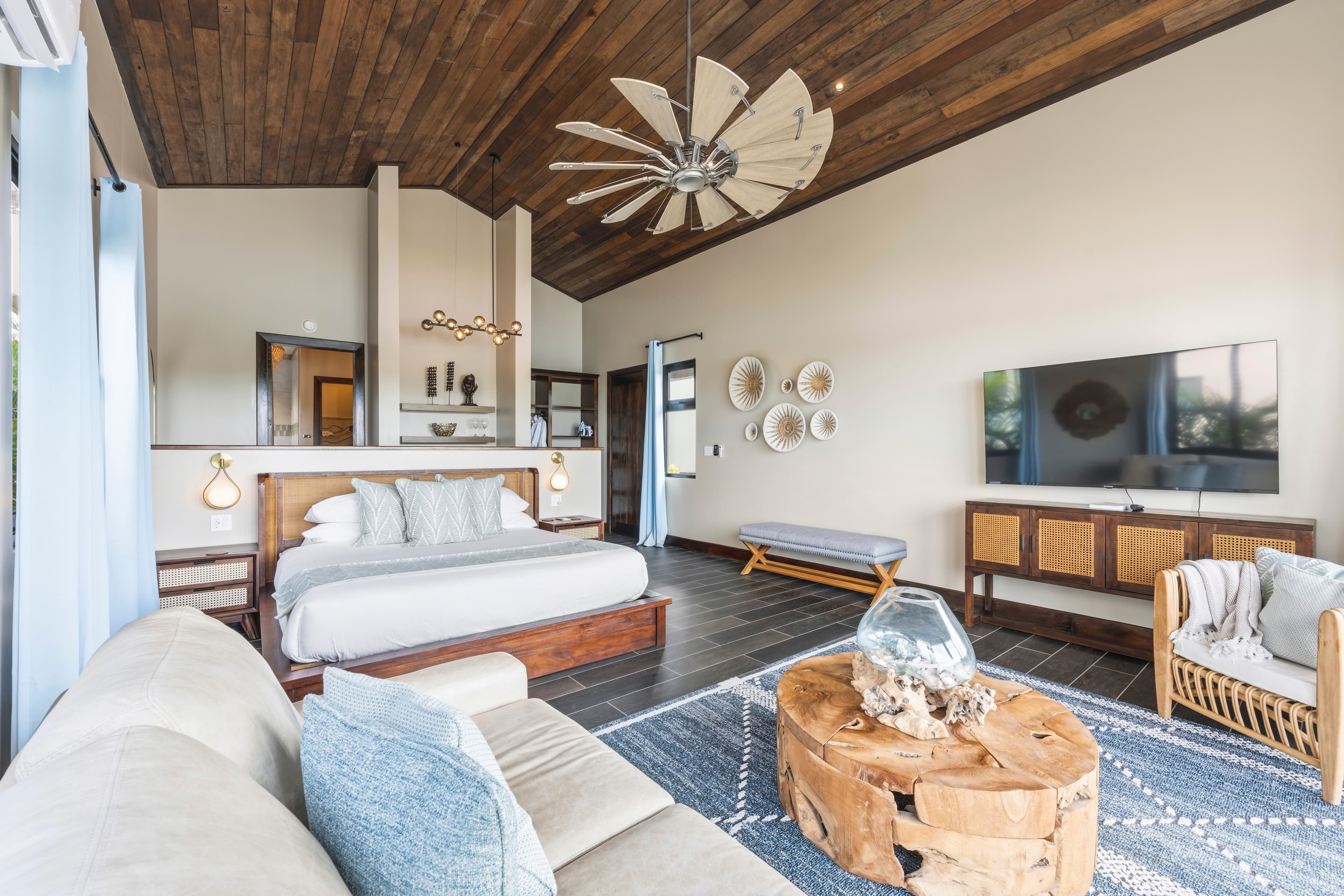 A spacious, modern bedroom with a wooden ceiling, large bed, and stylish furnishings.