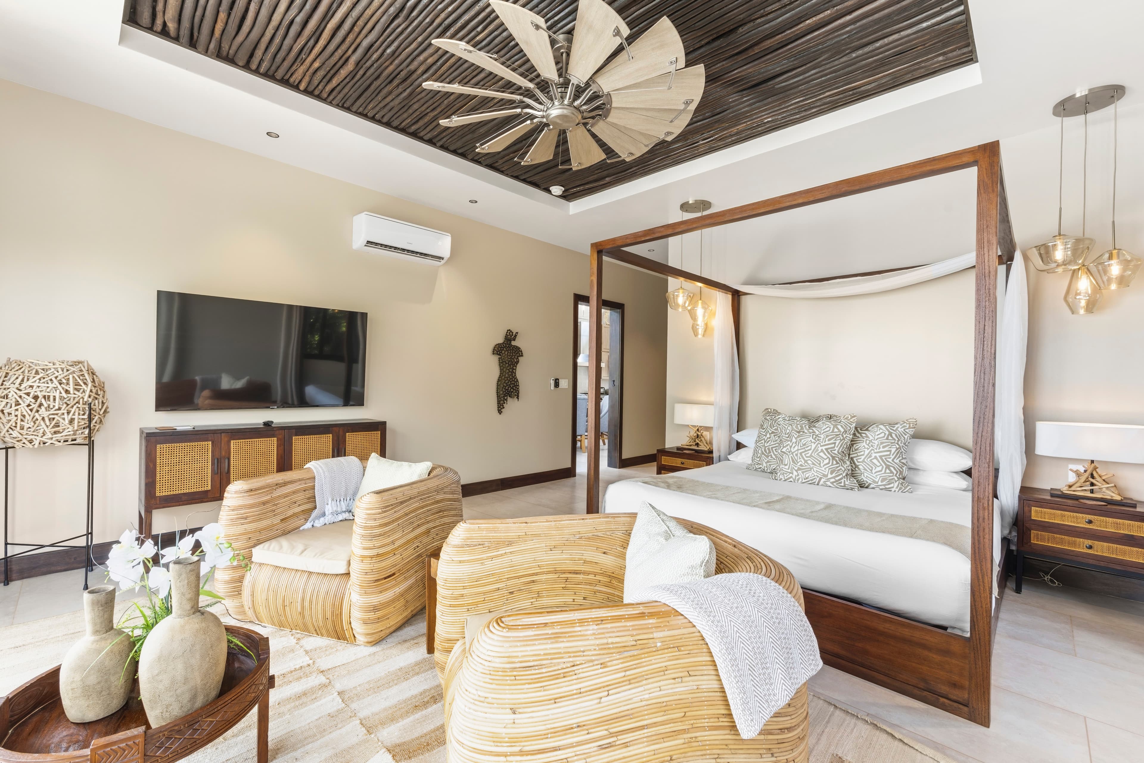 A stylish bedroom featuring a four-poster bed, wicker chairs, and modern decor.