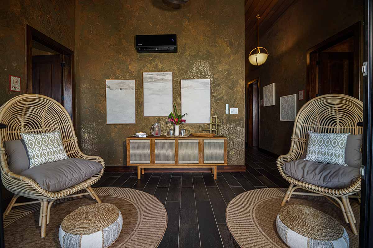 A stylish entryway features two woven chairs, a decorative table, and textured walls.