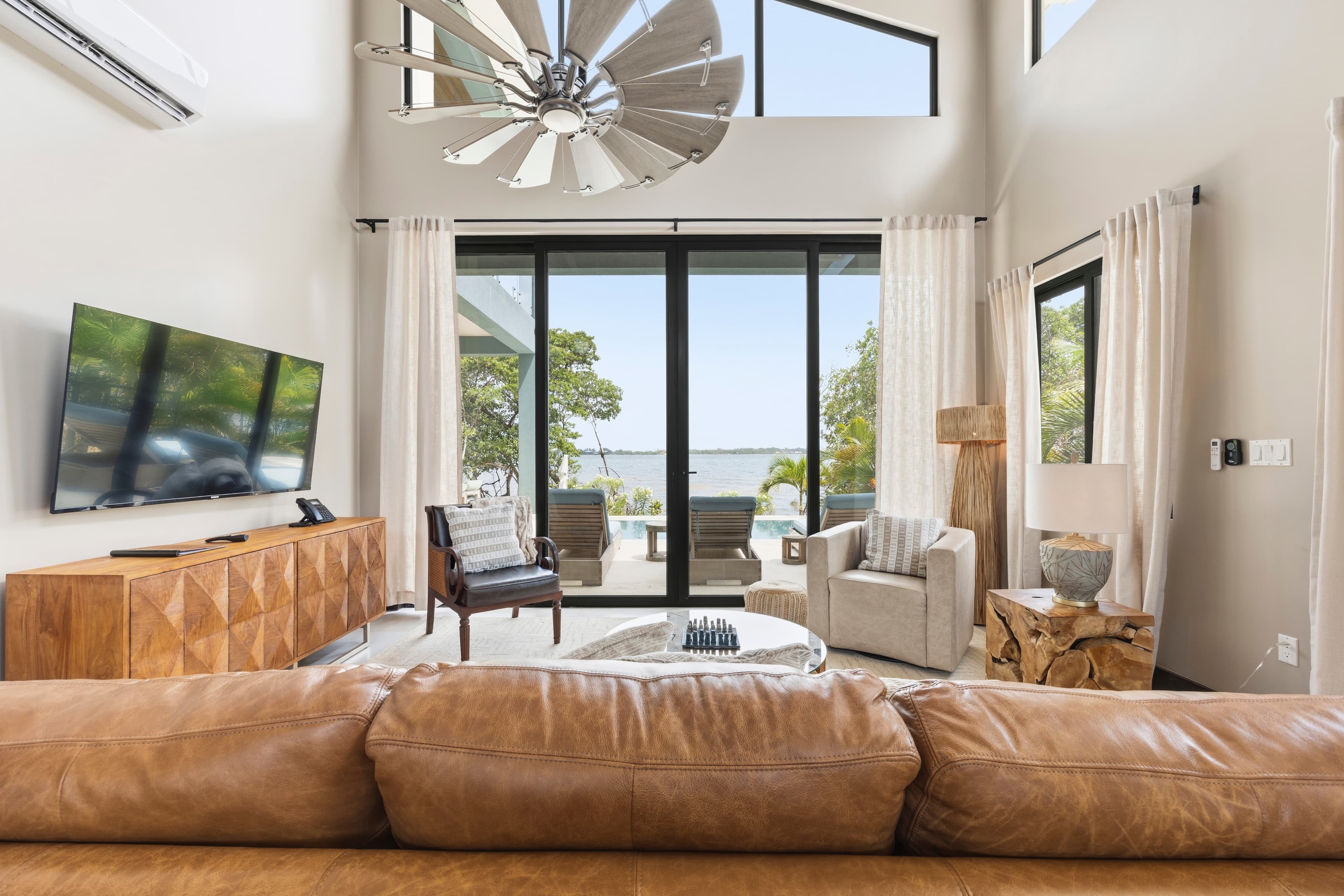 Modern living room with large windows, lake view, and stylish furniture.