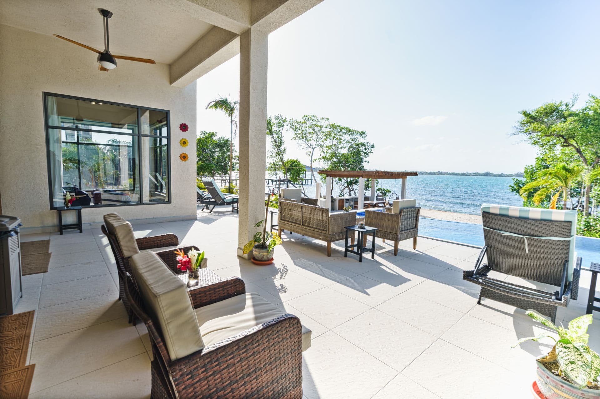 A modern patio featuring comfortable seating, potted plants, and a view of a serene body of water.