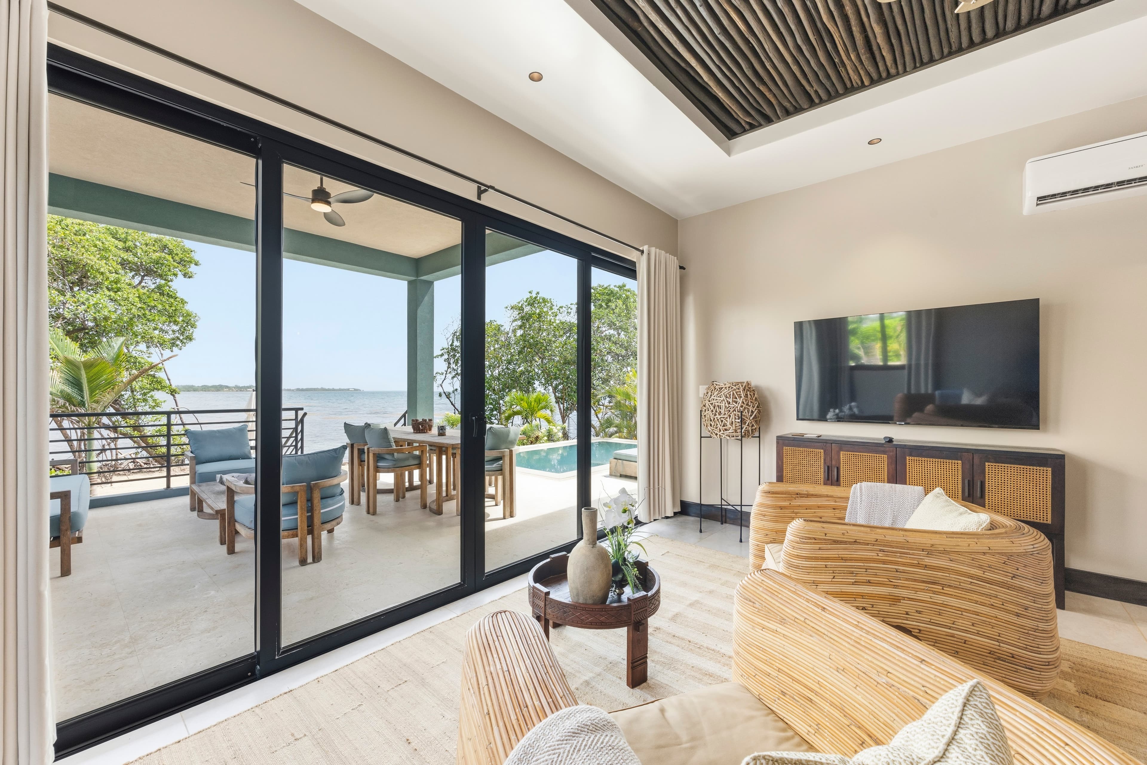 Bright living room with large glass doors opening to a scenic outdoor patio and pool area.