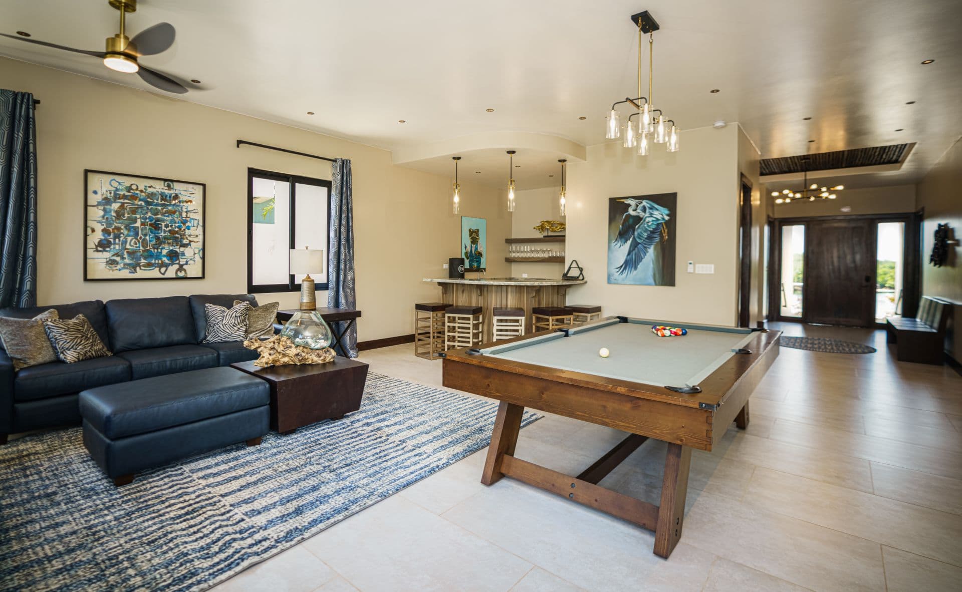 A spacious living area featuring a pool table, a blue sofa, and a bar counter.