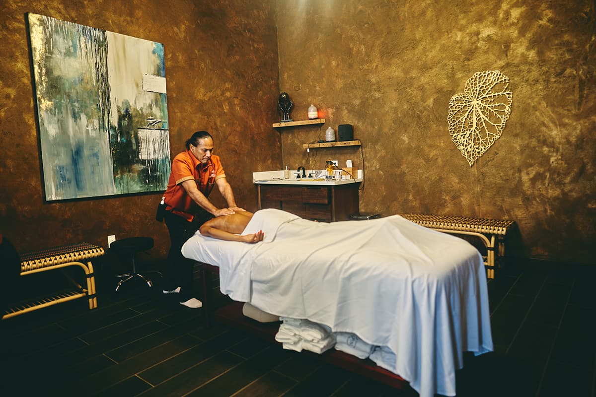 A massage therapist provides a treatment to a client in a calming spa environment.