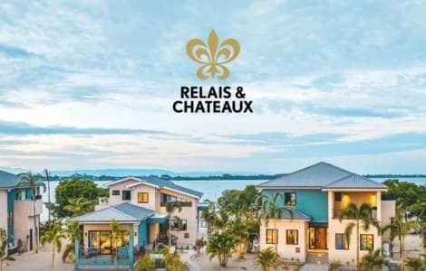 A scenic view of luxury villas by the water with the Relais & Châteaux logo above.