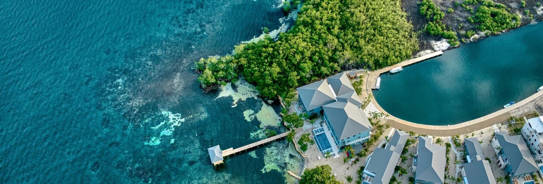 Aerial view of a resort surrounded by turquoise water and lush greenery.