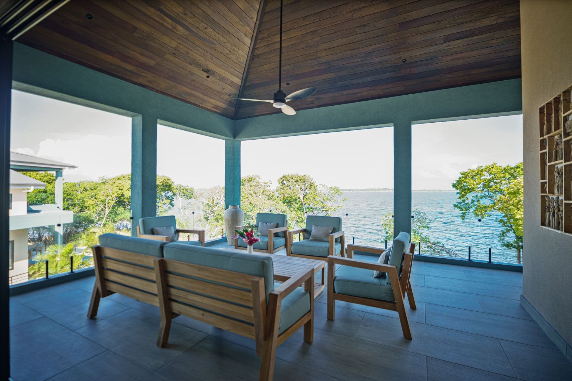A stylish outdoor seating area with wooden furniture and a view of the water and trees.