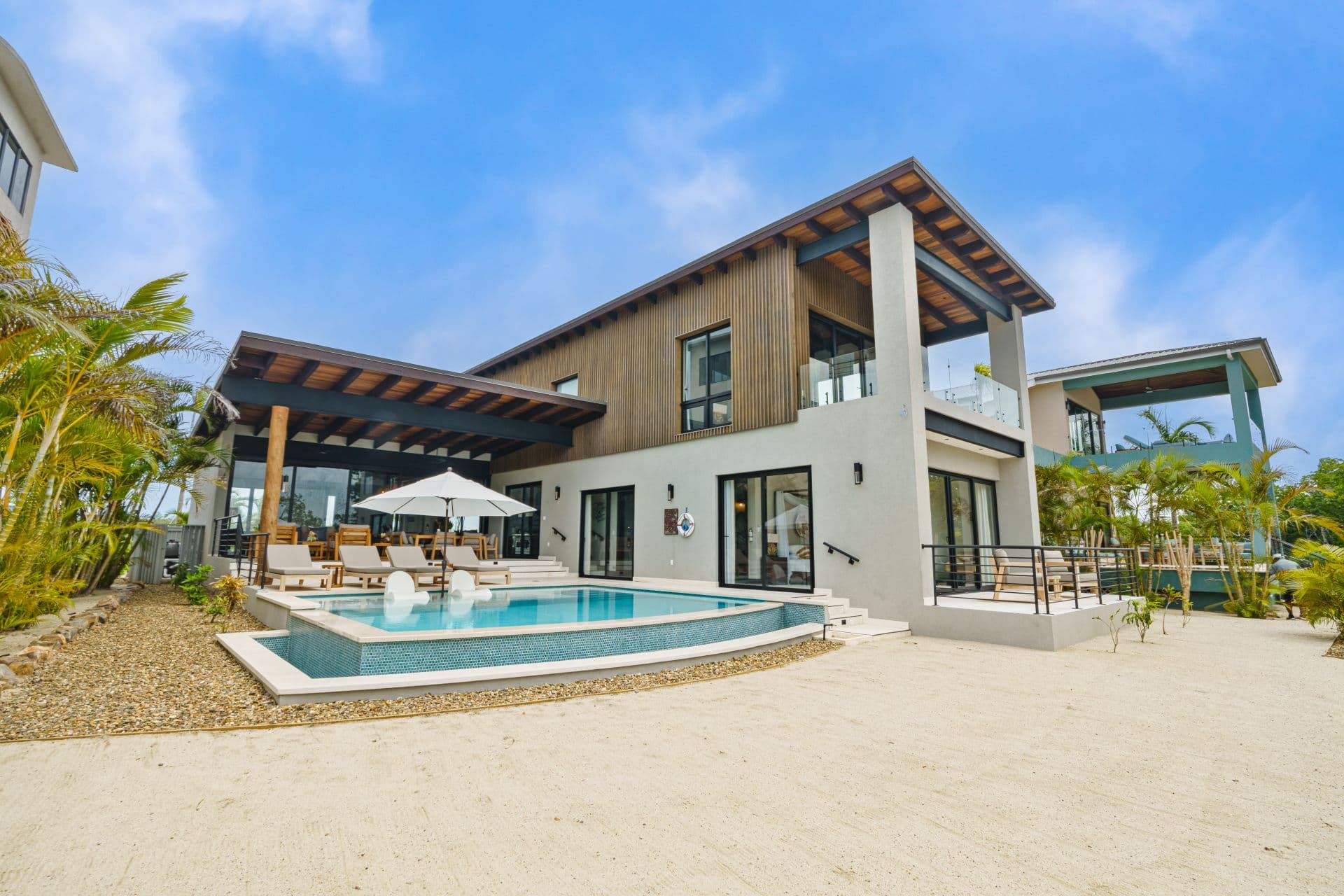 Modern two-story villa with a pool and outdoor seating area surrounded by tropical landscaping.