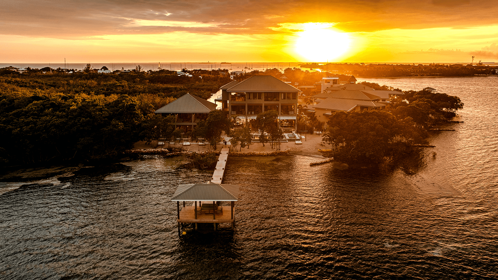 A picturesque sunset over a waterfront property with a dock and lush greenery.