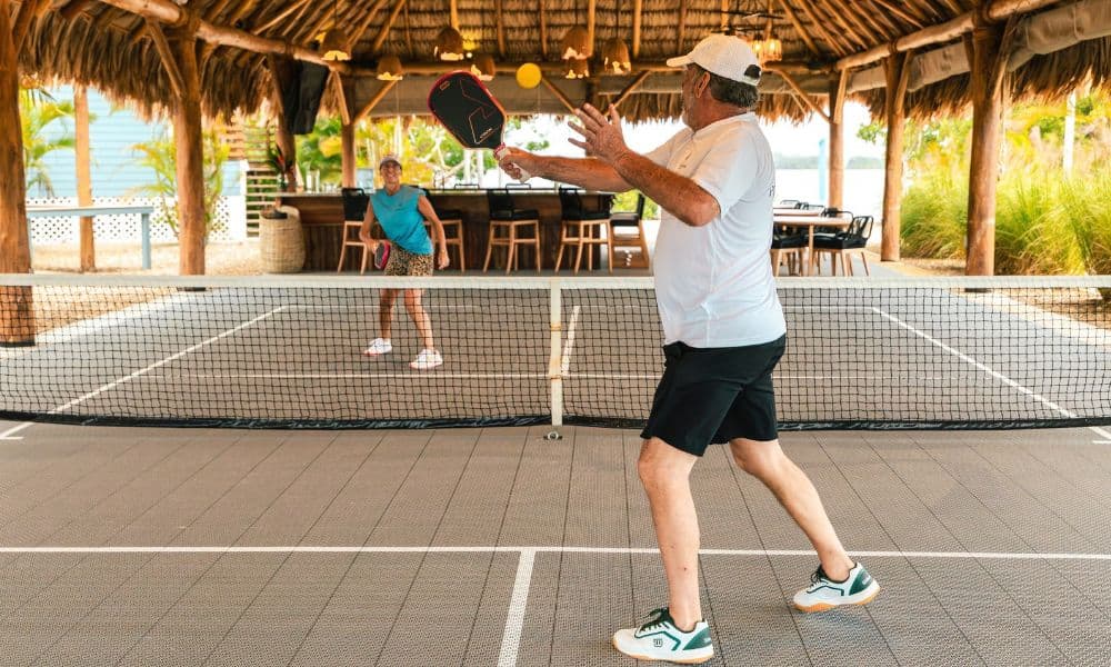 Two guests play pickleball on a covered court at Prana Maya Island Resort in Belize.