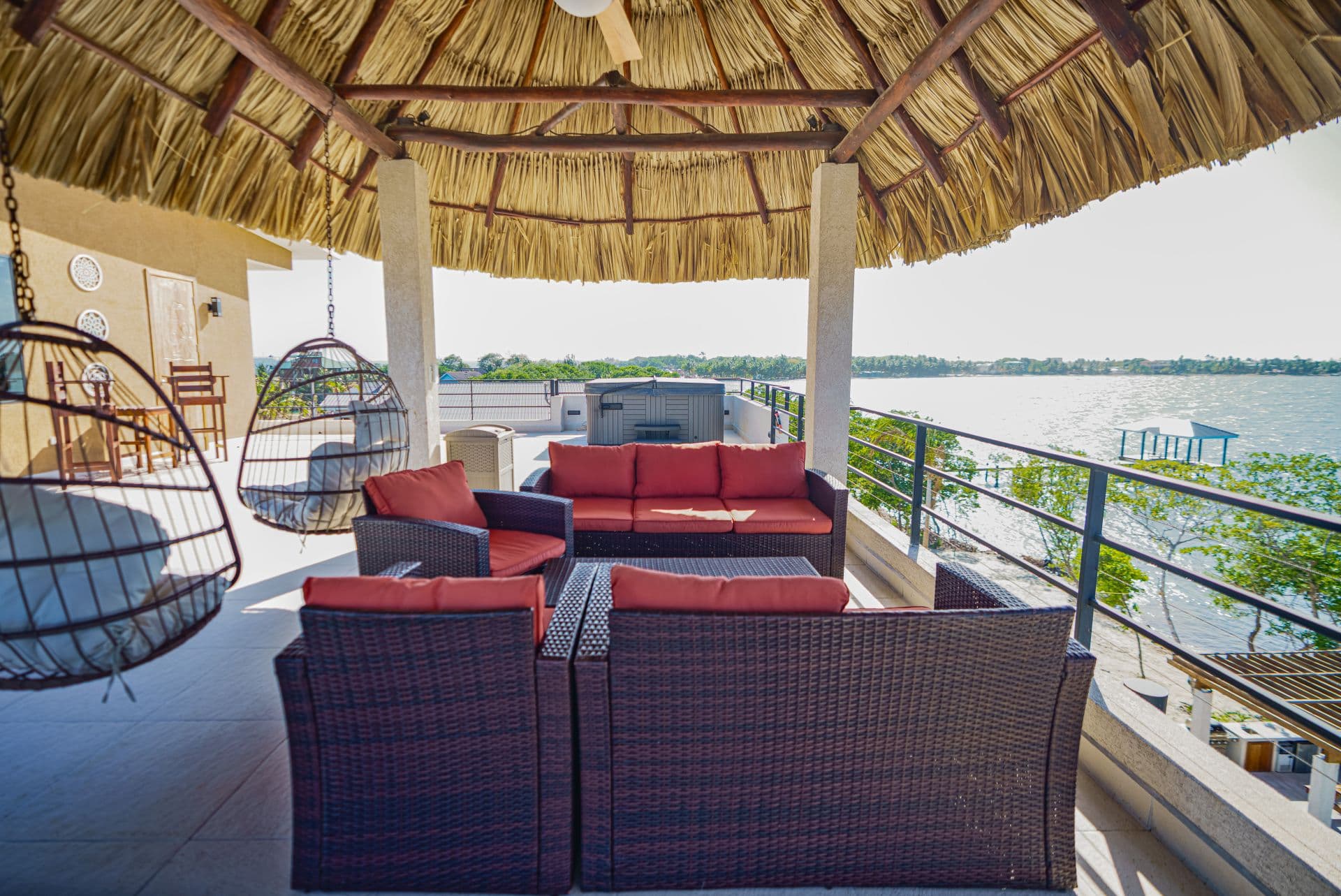 A cozy seating area under a thatched roof overlooking a serene waterfront.