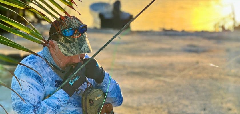 Angler tying a fly fishing knot at sunrise on the flats near Prana Maya Island Resort in Belize.