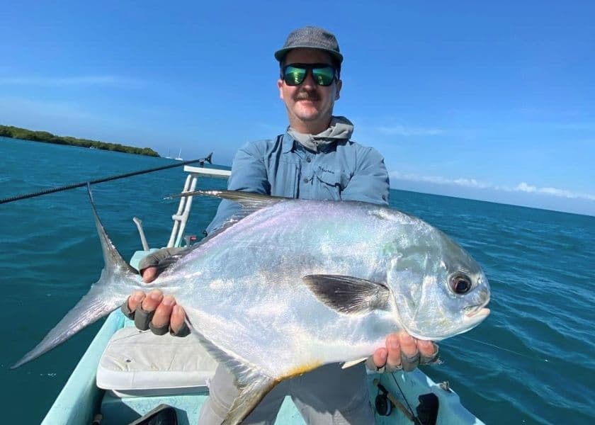 Angler holding a permit caught while fly fishing the flats near Prana Maya Island Resort in Belize.