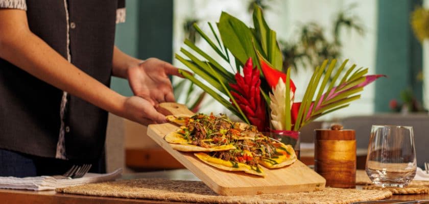 Server presenting flatbread dishes at The Grove restaurant at Prana Maya Island Resort in Belize.